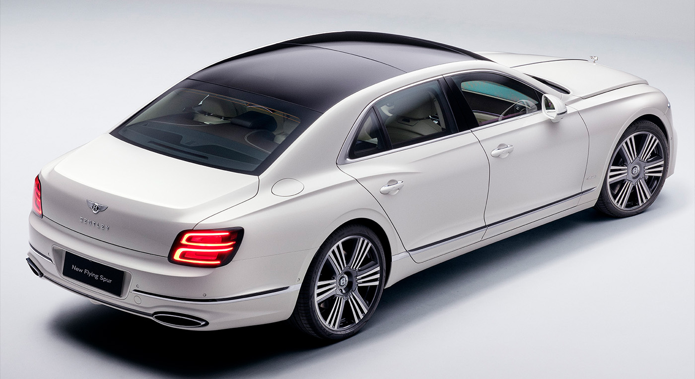 Luxurious white sedan with a sleek design and tinted windows, viewed from above. The car exudes elegance with its streamlined body and stylish rear lights.